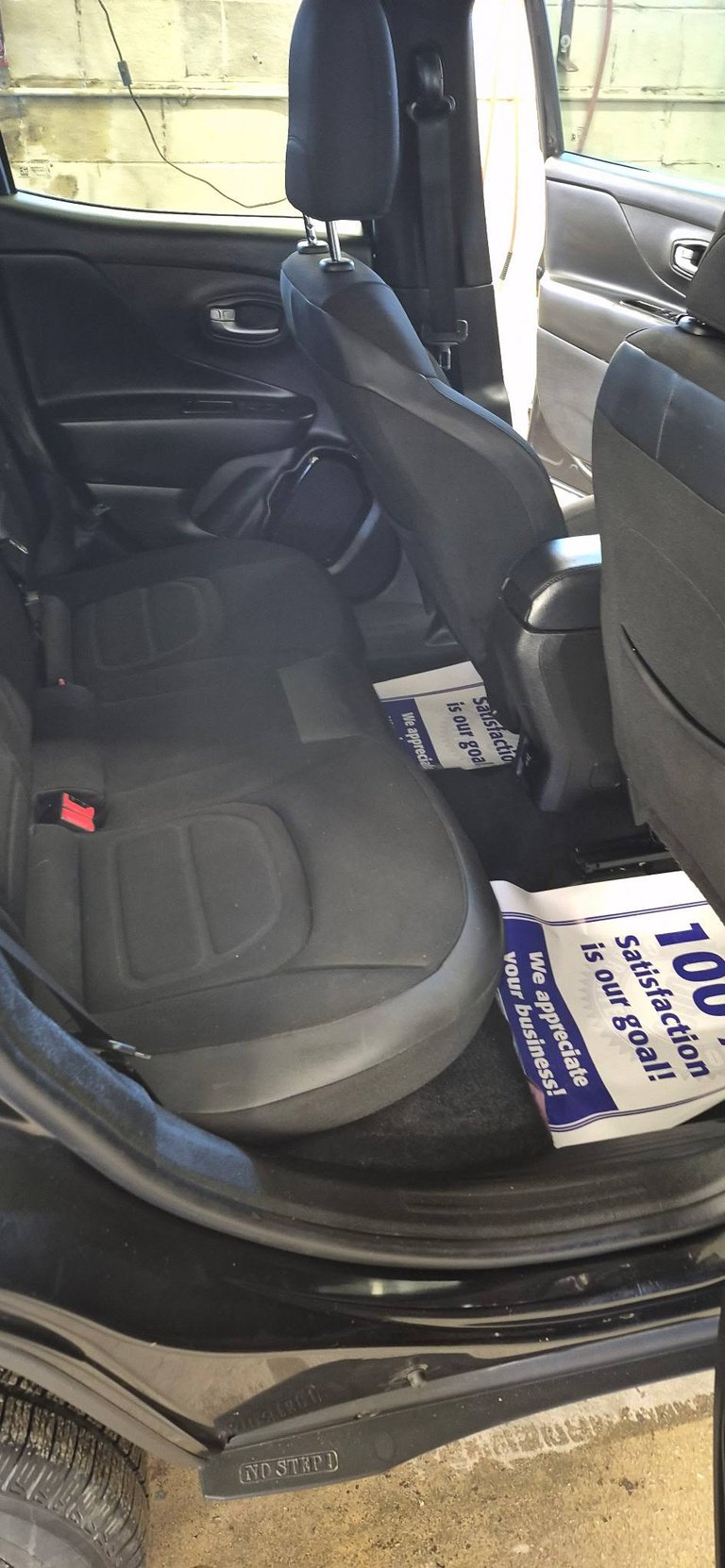 Interior view of car with open drivers side door showing black leather seats and promotional flyers on floor