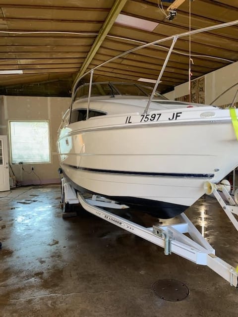 White speedboat with registration IL 7597 JF on trailer inside a storage garage or warehouse