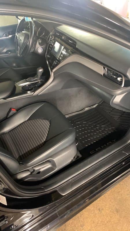 Interior view of a modern car showing steering wheel, dashboard, and front seats with black and gray upholstery