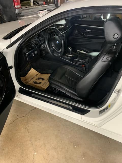 White BMW convertible with drivers door open showing black interior with leather seats and steering wheel