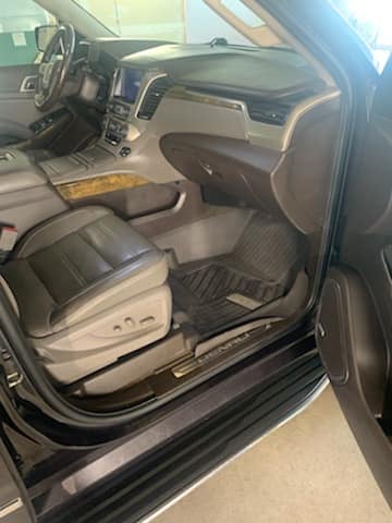 Interior view of a pickup truck showing the dashboard, steering wheel, leather seats, and open driver side door